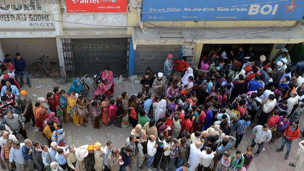 Indian people queue outside a bank as they wait to deposit and exchange 500 and 1000 Rupee notes in Amritsar