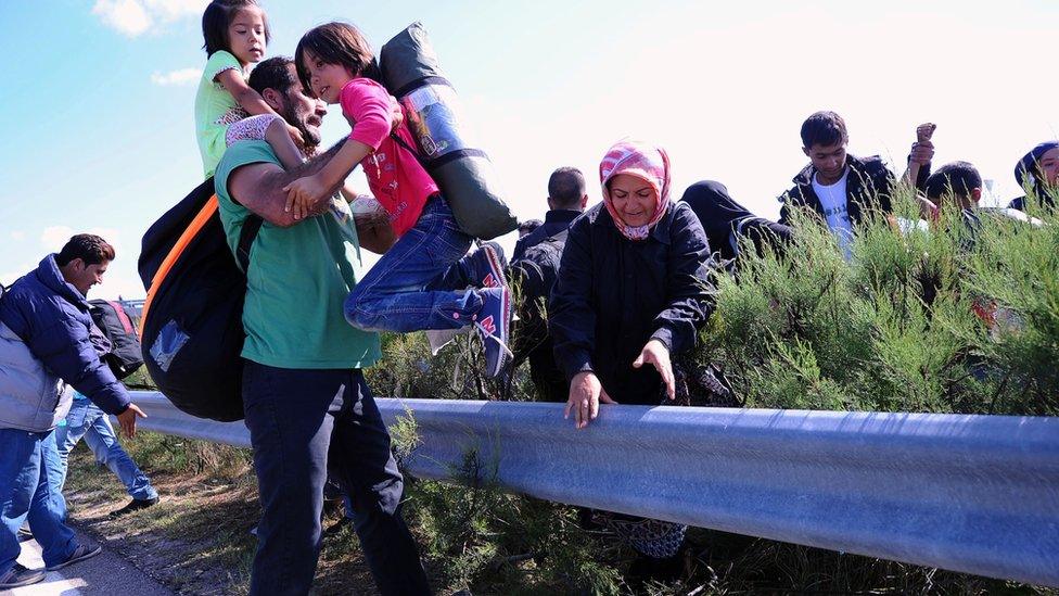 A migrant family walks across the middle lane of M5 highway after they broke through a police line near a camp at Roszke village at the Hungarian-Serbian border on 9 September 2015