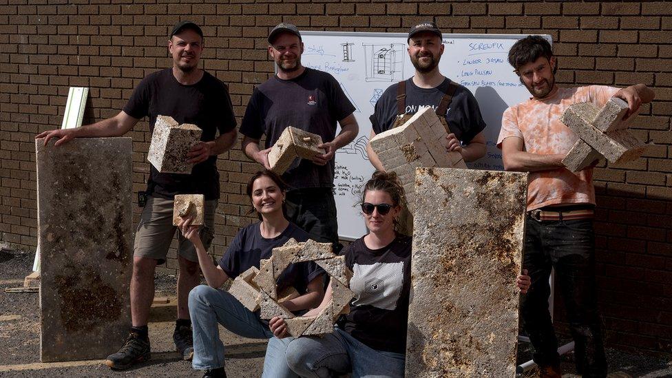 Six people holding sections of the mushroom structure