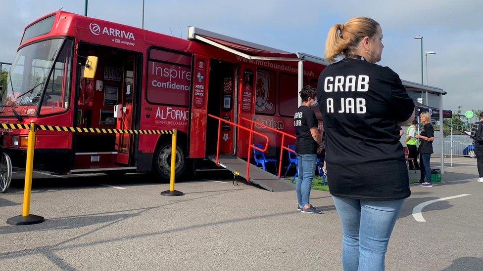 Staff member wearing 'Grab a Jab' T-Shirt stands next to Boro Bus