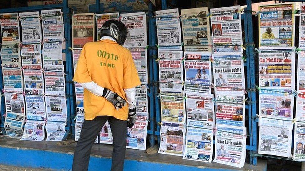 Motorcycle taxi member looks at newspapers at the entrance to the National Hospital and University Centre (CNHU) in Cotonou on April 6, 2021