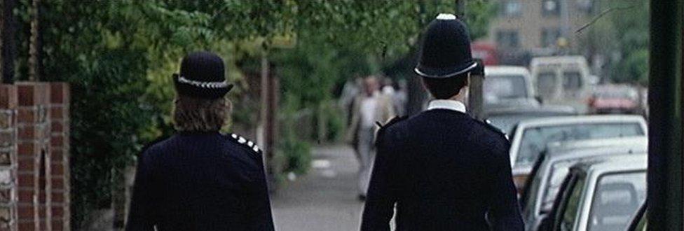 Two police officers walk down a road