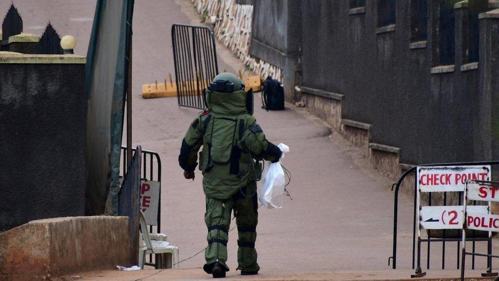 A bomb disposal expert dressed in his protective suit lays a cable as he prepares a controlled detonation of an explosive device outside a Pentecostal church, Lubaga Miracle Centre, in the Lubaga suburb of south Kampala, Uganda September 3, 2023.