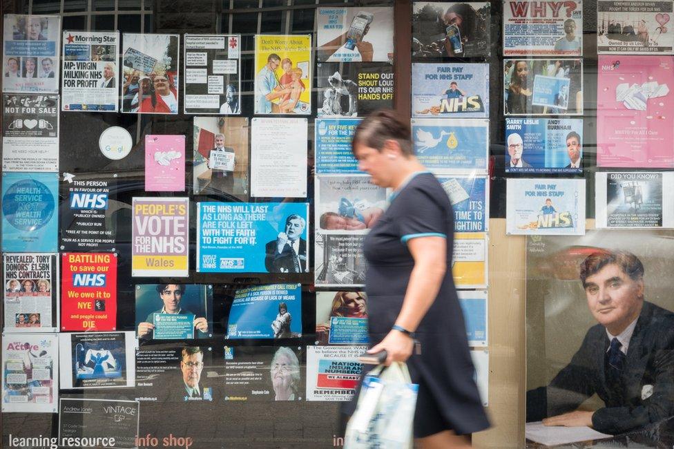 A woman passes a photograph of founder of the National Health Service, Aneurin Bevan, displayed in a shop window in Tredegar in Wales