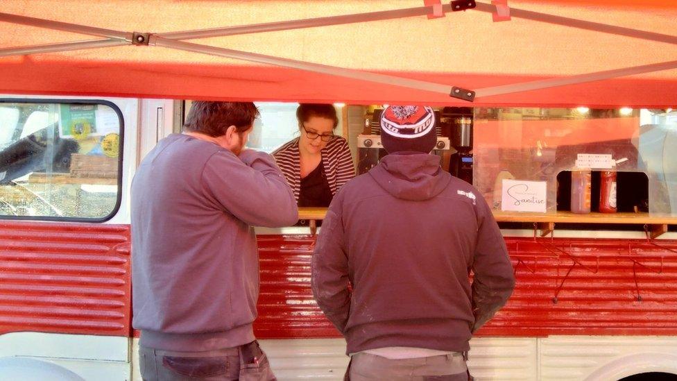 Two tradesman standing outside a food van