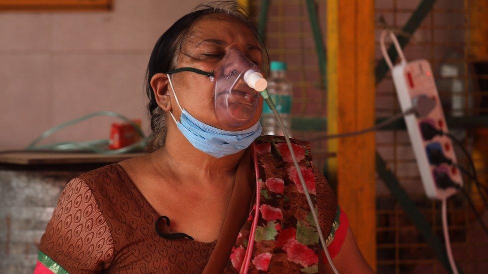 A woman in India breaths through an oxygen mask