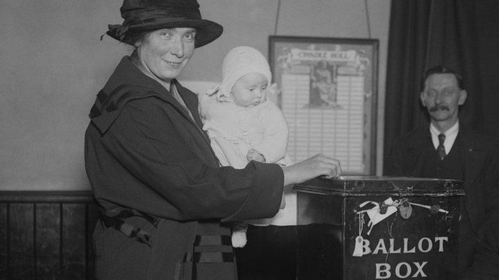 Mother posts vote in ballot box in South Dulwich while holding baby