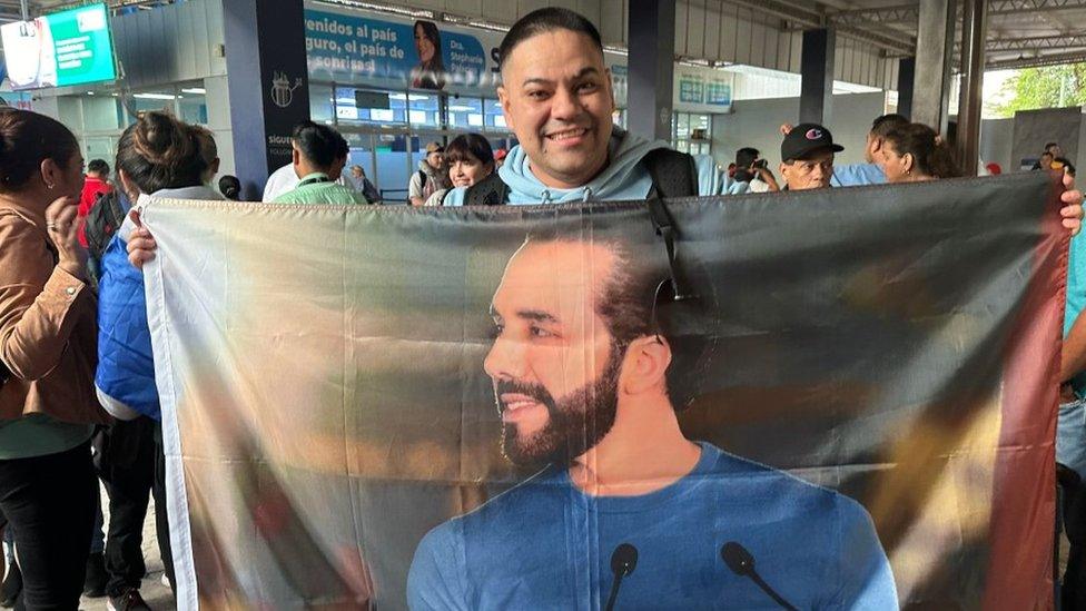 Francisco Villegas holding a flag with President Nayib Bukele's face