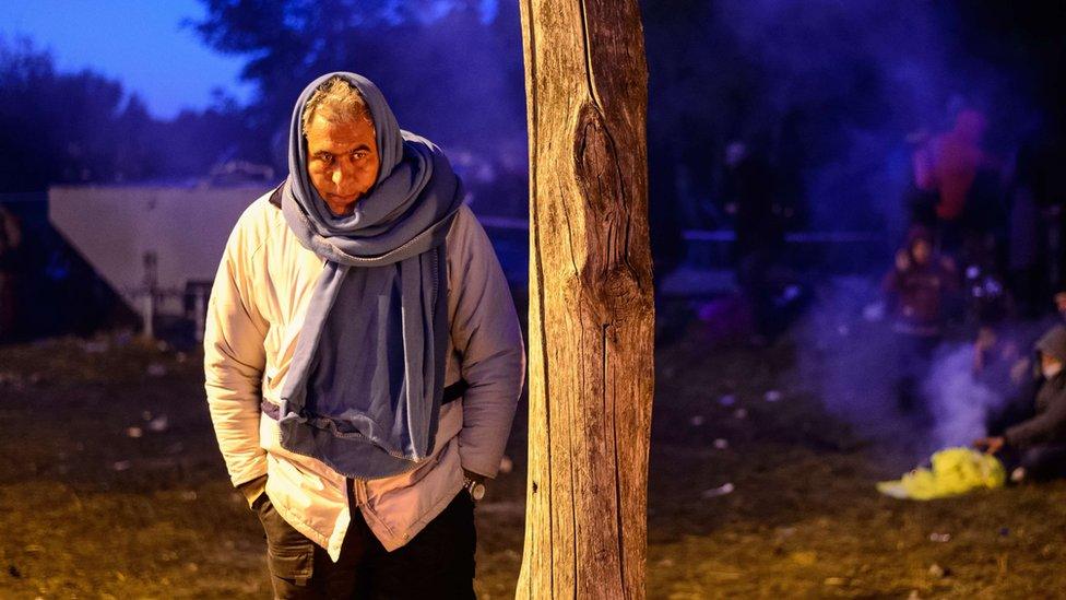 A man with a blanket wrapped around his head waits with other migrants and refugees to be transported to a refugee centre after crossing the Croatian-Slovenian border near Rigonce, Slovenia, on October 24, 2015