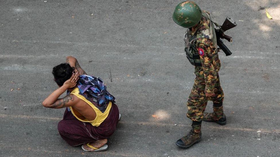 A soldier stands next to a detained man during a demonstration against the military coup in Mandalay on March 3, 2021