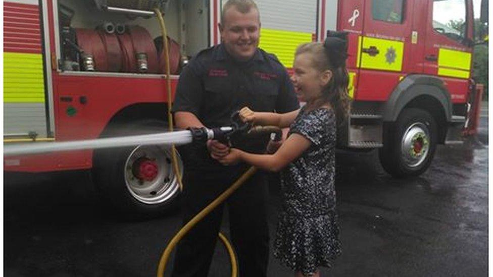 Kelcea holding a fire hose