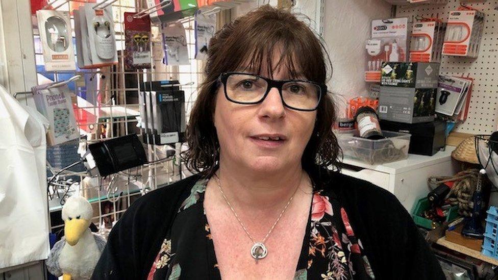 A white woman with dark hair working in a hardware shop