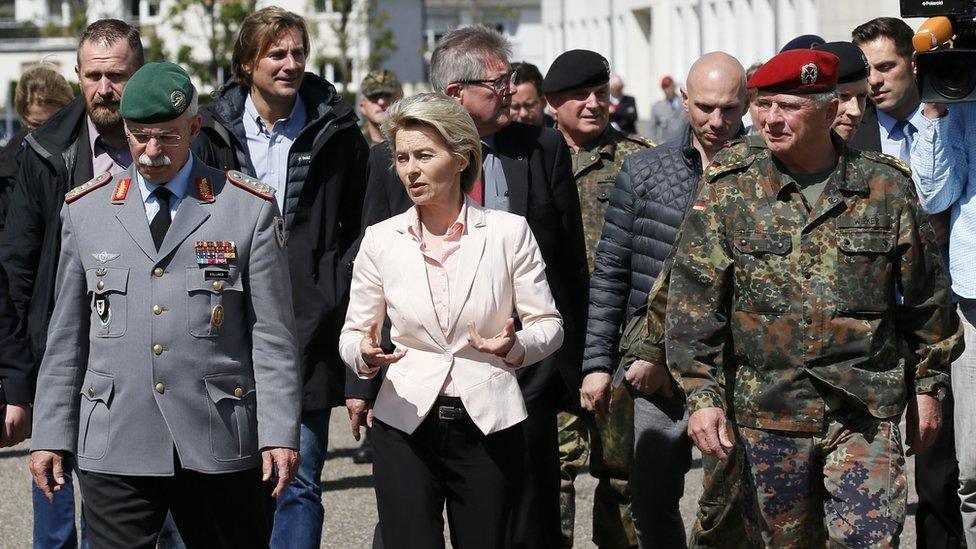 politician flanked by military people