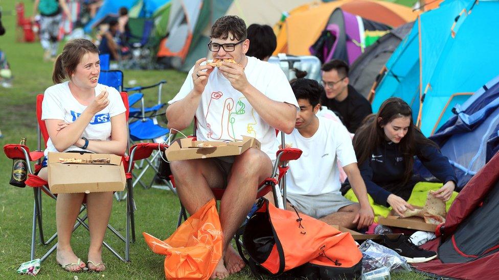 People eat pizza in the queue