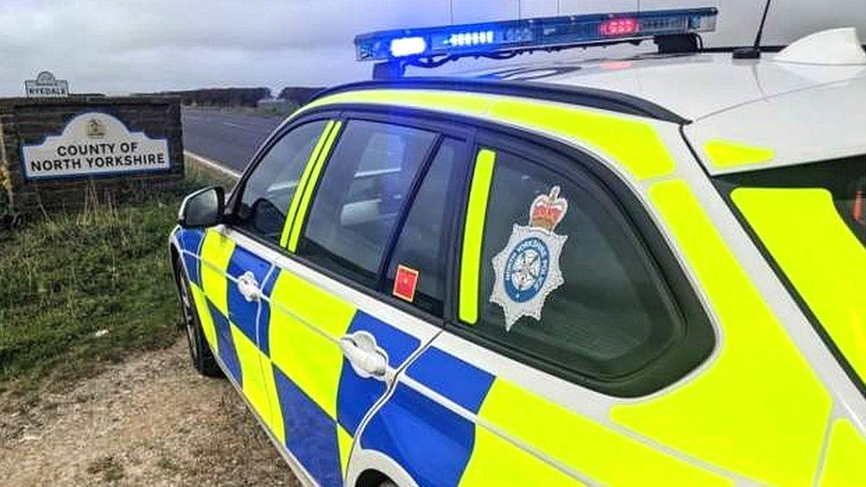 Police car by North Yorkshire sign