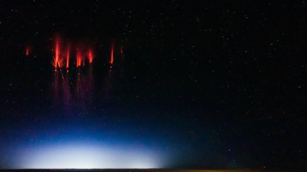 Several red spark-like features with spidery trails, looking almost like fireworks against a starry sky