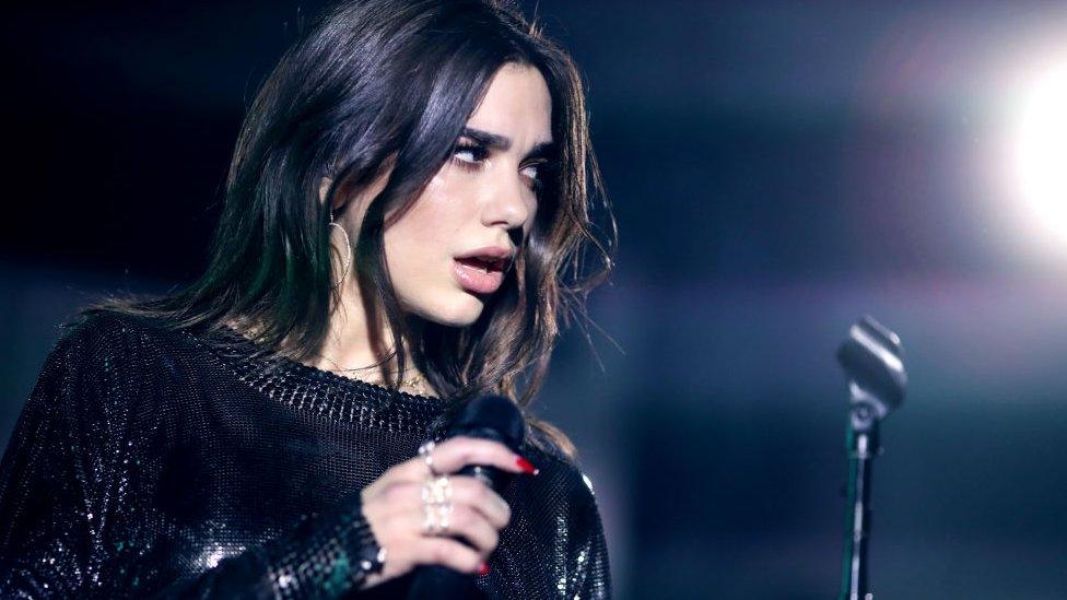 dua lipa holding a microphone