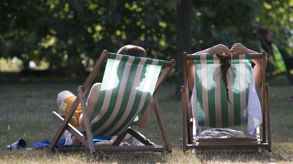 A couple relax on deckchairs in the warm weather in Hyde Park