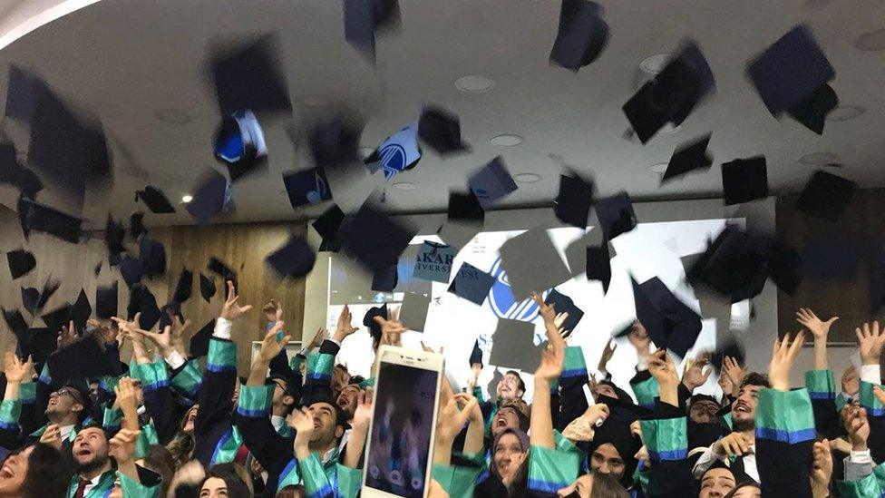 Graduates throw their mortar board hats in the air