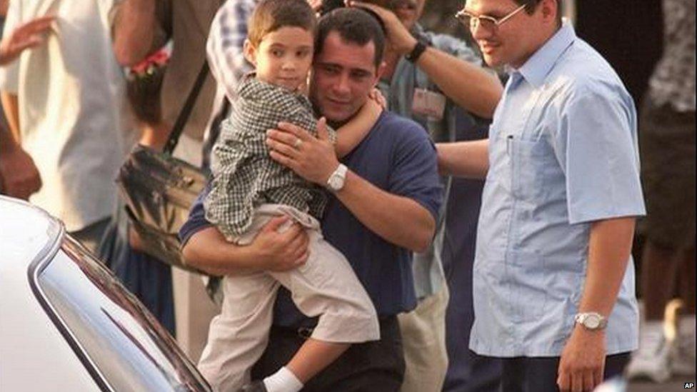 Juan Miguel Gonazalez carries his son Elian Gonzalez to a car as schoolmates wave upon their arrival to Havana's Jose Marti airport, Wednesday in June 2000