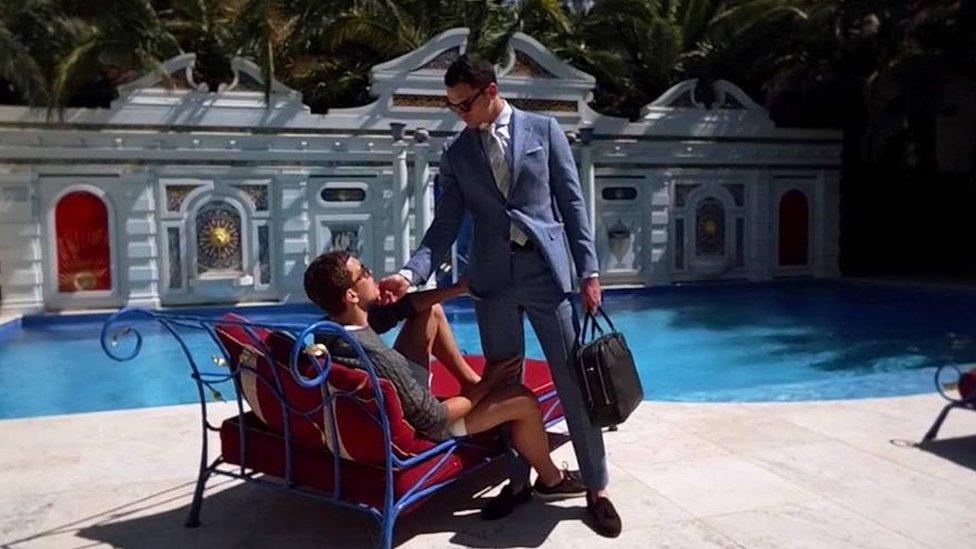 Two male models hold each other next to a swimming pool in an advert