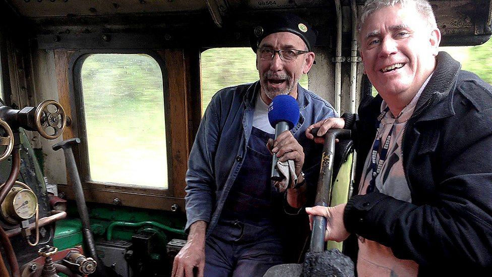 Ali Brownlee interviewing man on train