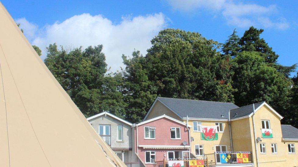 Baneri Cymru, Owain Glyndŵr a baner Sir Fynwy ar y tai yma, sydd â golygfa penigamp o'r Maes // The locals in these houses have a bird's eye view of the Maes