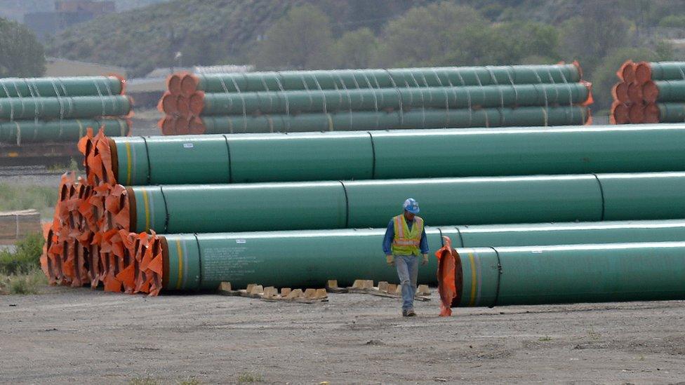 A workman walks past steel pipe to be used in the construction of the Trans Mountain expansion project