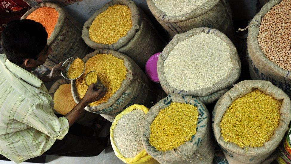 An Indian tradesman takes lentil samples at the wholesale market in Hyderabad, India