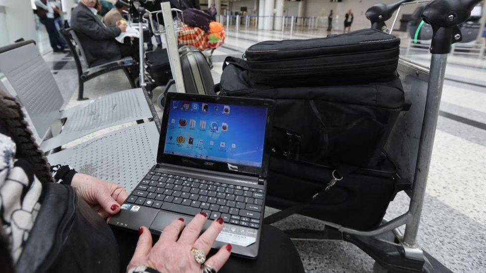 A Syrian woman travelling to the United States through Amman opens her laptop before checking in at Beirut international airport