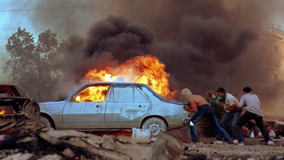 Palestinians burn cars as protests flared near the West Bank town of Ramallah, 2000