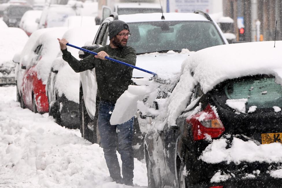 A man clears snow from his car in Auchterarder, Perth and Kinross, on 14 January 2021