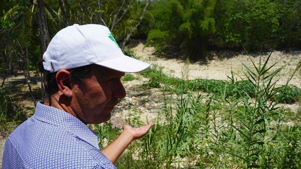 A man looks at the dry riverbed of the Pagee