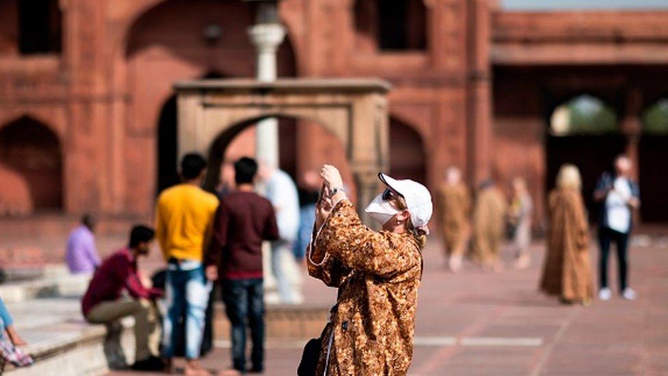 A tourist, wearing a facemask amid concerns over the spread of the COVID-19 novel coronavirus, visits the Jama Masjid mosque in the old quarters of New Delhi