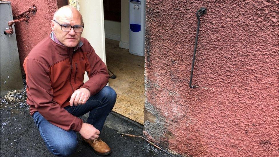 Sinn Féin MP Paul Maskey inspects some of the damage that was caused