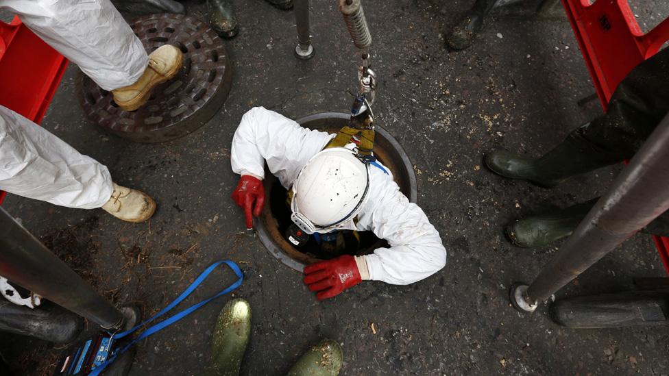 Thames Water sewer supervisor Vince Minney, emerges from a manhole in Whitehall after working in the Regent sewer in London on December 11, 2014