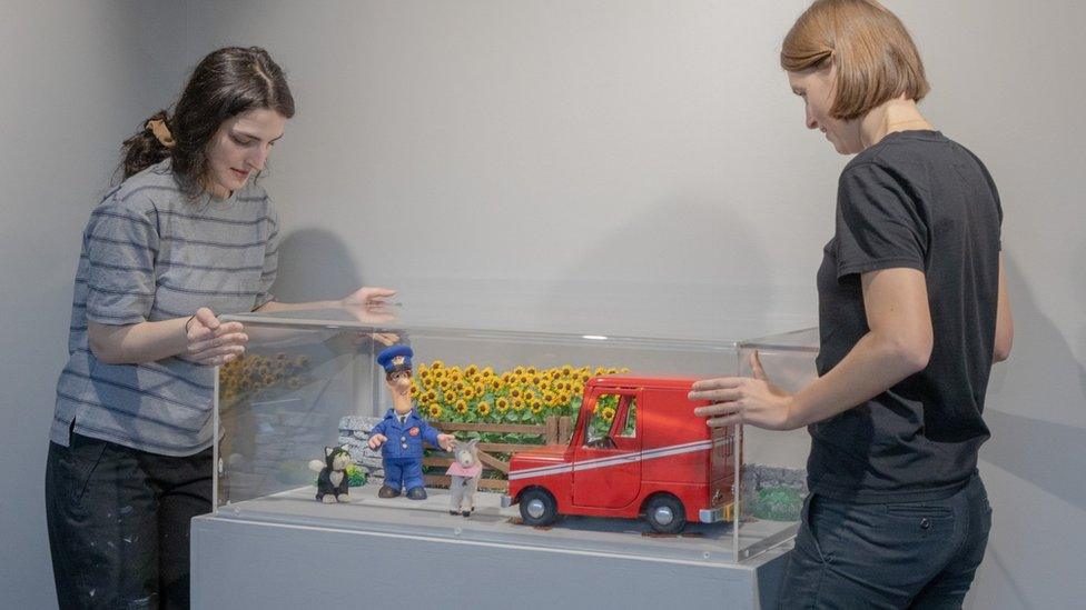 Curators moving a Postman Pat exhibit