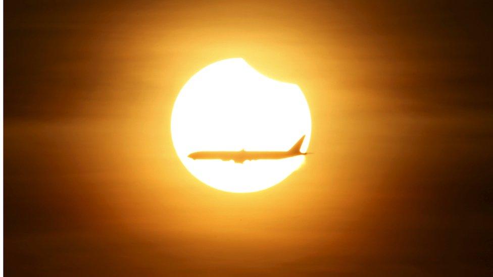 Plane flies across partial eclipse in Singapore