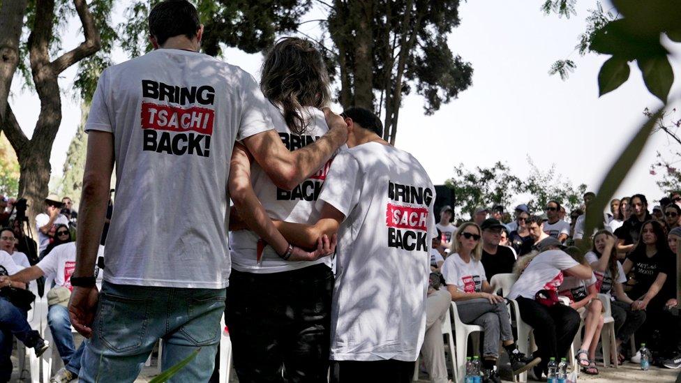 Attendees at Maayan's funeral stand with backs to camera