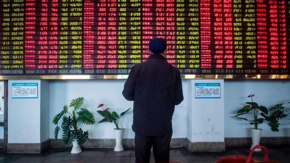 Man stands in front of stock market boards in China