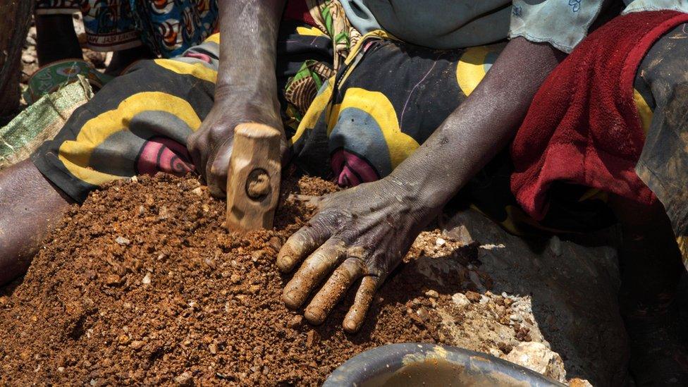 A woman breacks stones containing cassiterite ore at a mine in the Szibira district, Democratic Republic of Congo, in April 2009