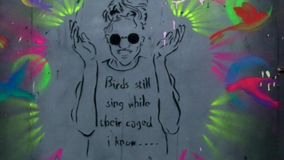 Street art shows design of man with the words 'Birds still sing while their caged I know...'