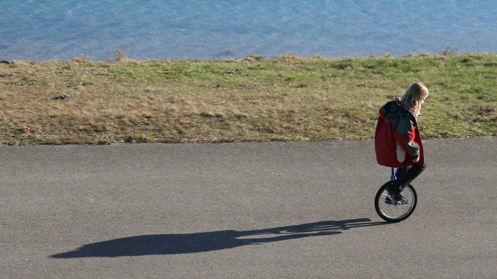 a-person-with-long-blonde-hair-rides-a-unicycle