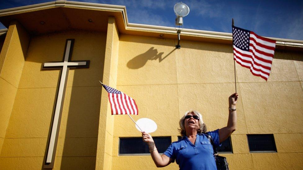 A woman holds American flags outside Centro de la Familia evangelical church January 28, 2012 in Orlando, Florida.