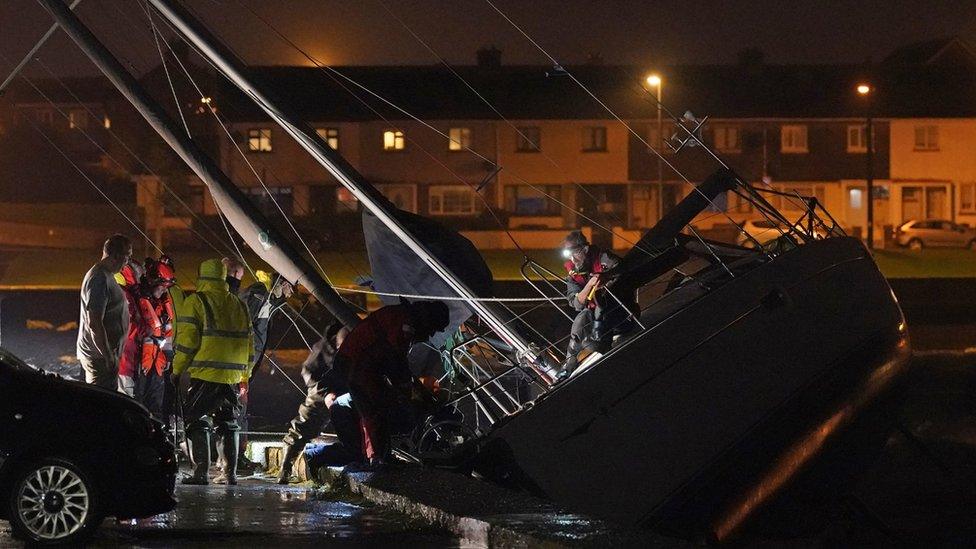 Members of Irish Coast Guard inspect a boat that broke free from its birth and crashed into the harbour in Co. Waterford during Storm Betty