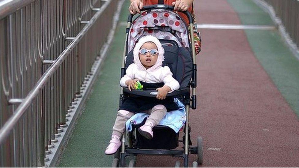 A woman pushes a baby carriage on an overpass in Beijing.