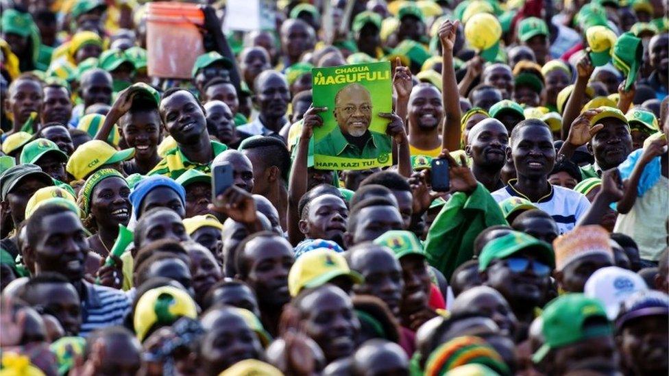 A man holds up a poster of presidential candidate John Magufuli during a ruling Chama Cha Mapinduzi (CCM) rally in Dar es Salaam, Tanzania, on October 21, 2015