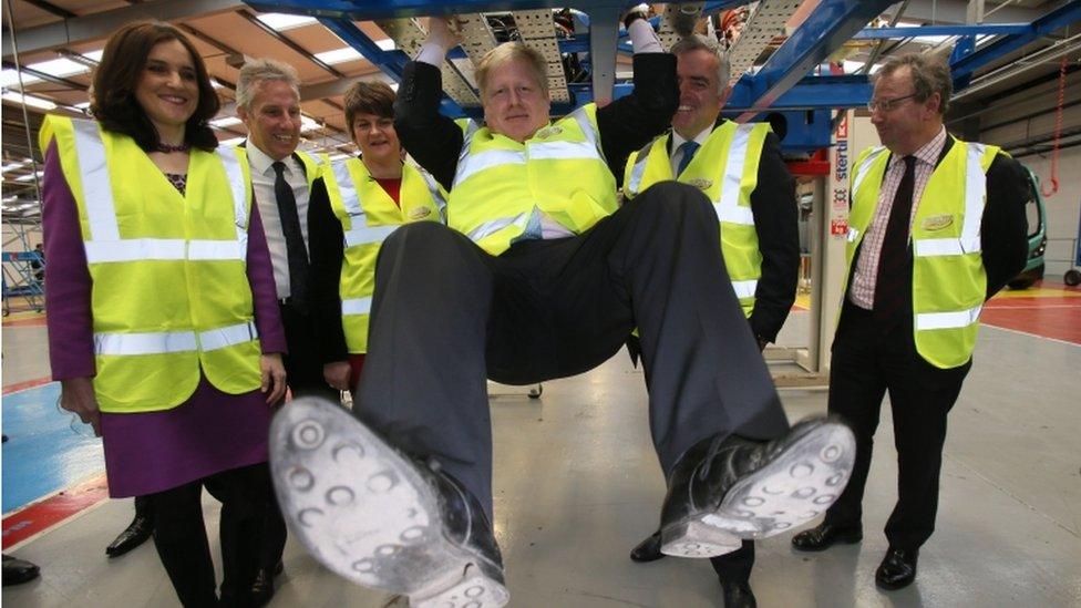 Boris Johnson swinging on the chassis of a Boris Bus at the Wrightbus plant in Ballymena