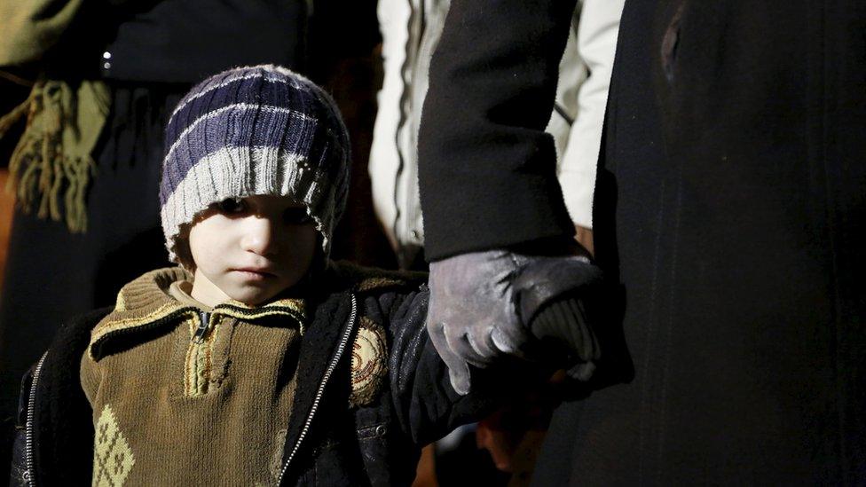 A Syrian boy waits with his family in Madaya