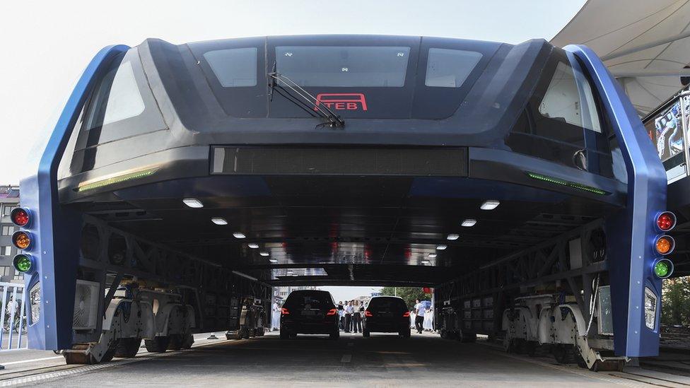 People look at the Transit Elevated Bus TEB-1 run past vehicles as they conducted a test run in Qinhuangdao, north China"s Hebei Province